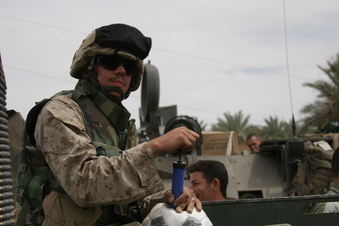 Haqlaniyah, Al Anbar, Iraq.-- Cpl. Kennedy inflates soccer balls in the back of a Humvee for Iraqi children.  Soccer balls are a favorite among the kids.  Marines handed out other items like school supplies and Beanie Babies.  Some parents received four or five bags of school supplies for all their children.   (Photo by LCpl. Marc Fencil. )