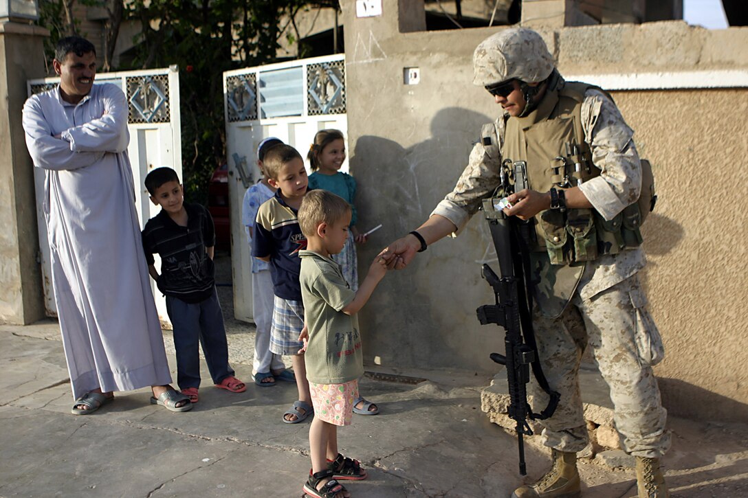 Haqlaniya, Al Anbar, Iraq (May 1, 2005)--Lance Cpl. Glibert R.Miera, 27 of Taos, NM.,  and infantrymany with 3rd battalion, 25th Marine Regiment, gives candy to children in Iraq. As a former educator Miera has a special place for children in his heart.(Official USMC Photo by Corporal Ken Melton)