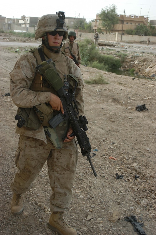 AR RAMADI Iraq (June 27, 2005) - Lance Cpl. Benjamin L. Griffith, a machine gunner and instructor with the Combine Action Platoon, Company B, 1st Battalion, 5th Marine Regiment, walks down a street with a member of the Iraqi Security Forces trailing close behind during a mission in the city here June 26 with Company C Marines. Griffith, a 21-year-old from Cassoday, Kan., leads newly trained members of the ISF on missions in the city to hone their military skills. The 2002 Flint Hill High School graduate conducts daily missions in the city with his ISF counterparts. Griffith and eight ISF accompany squads with 1st Battalion, 5th Marines. Photo by: Cpl. Tom Sloan
