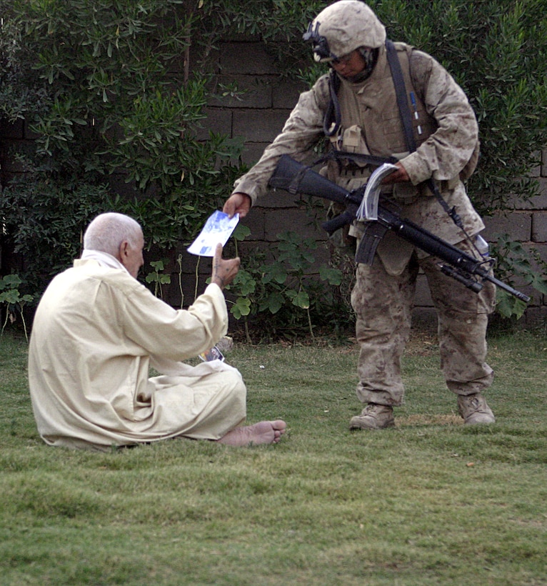 SAQLAWIYAH, Iraq - Private First Class Austen Wood, an infantryman with 4th Platoon, Company A, 1st Battalion, 6th Marine Regiment, hands an Iraqi citizen an informational flyer during Operation Hard Knock July 27.  Company A Marines searched dozens of houses throughout the small township outside Fallujah, looking for weapons, explosives and insurgent activity while gathering census data on the populace there.  The Marines apprehended one suspected insurgent supporter.