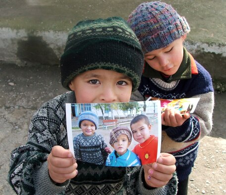 KARSHI, Uzbekistan -- An Uzbek boy at a local orphanage here holds up a picture given to him by visiting servicemembers Jan. 22 while his brother looks at a picture he was given.  The visit by Airmen, Soldiers and civilians from nearby Karshi-Khanabad Air Base was part of an ongoing humanitarian assistance program to Uzbek orphanages.  (U.S. Air Force photo by Tech. Sgt. Scott T. Sturkol)