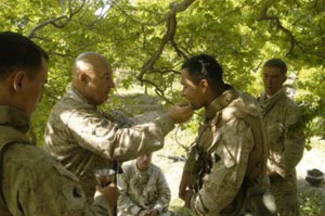 After a short Easter service, communion is given to a Marine by Lt. Eric Hoog, 58, Command Element Catholic chaplain and native of Philadelphia. The 15th Marine Expeditionary Unit (Special Operations Capable) is currently conducting security and stability operations here in the greater Baghdad area.