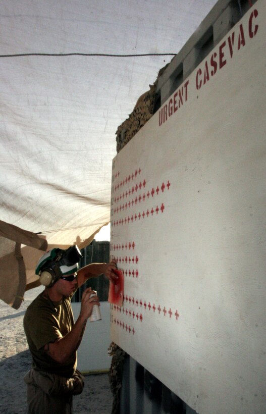 Lance Cpl. Daniel J. Burman, an airframes technician with Marine Medium Helicopter Squadron 161, paints a red cross on the squadron?s board charting the amount of urgent causality evacuations the squadron has done since Aug. 15, at Al Taqaddum, Iraq.