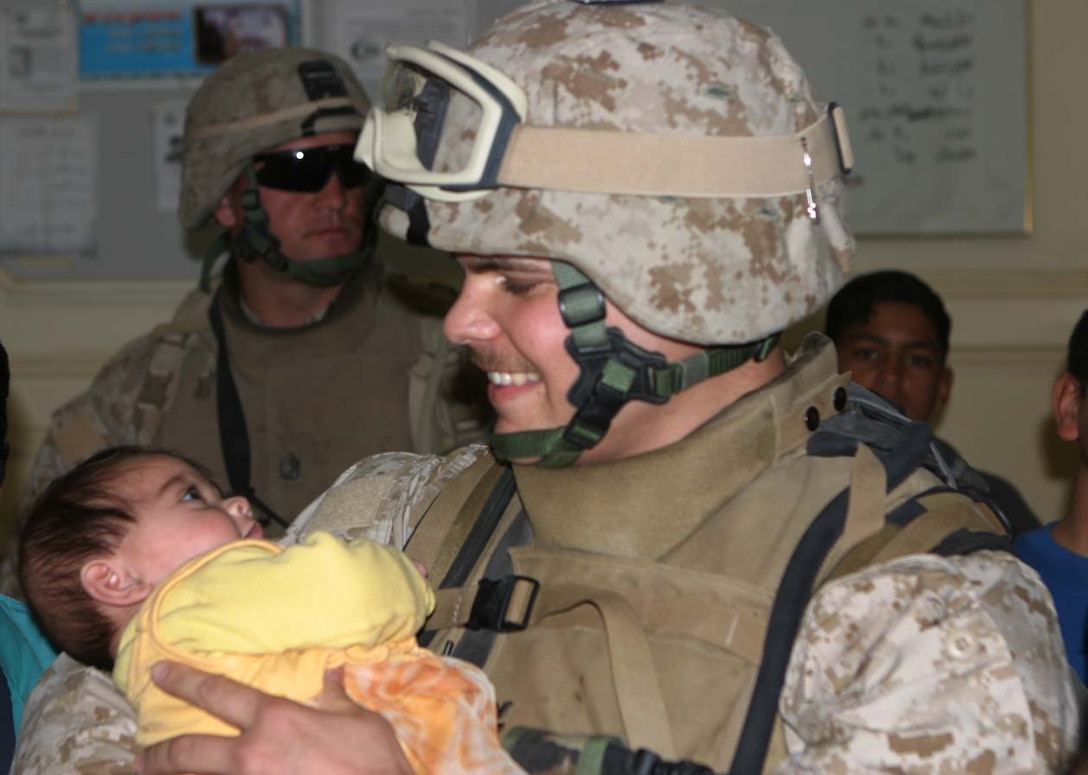 Working with the locals who came to get medical attention, Hospitalman 2nd Class Darren Piniero, is given an opportunity to hold an infant waiting to be seen.  Photo by Lance Cpl. Athanasios L. Genos