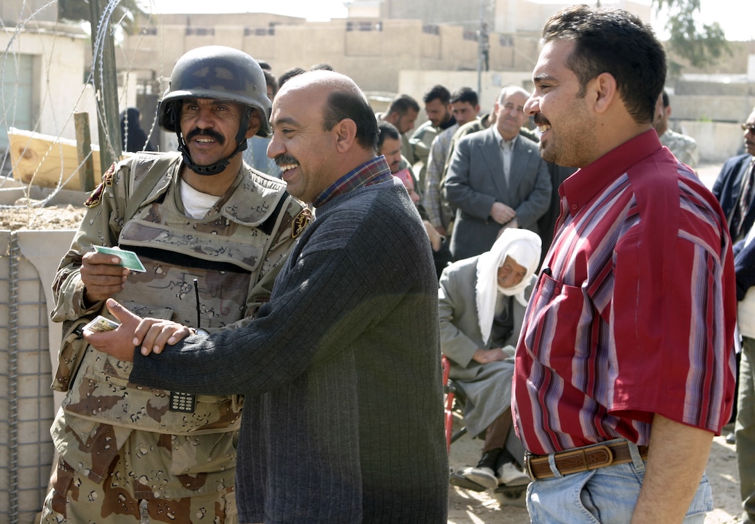 FALLUJAH, Iraq - A member with the Iraqi Interim Forces checks city residents here for proper identification before admitting them into the Jolan Park compound.  ISF and Iraqi police forces from the Public Order Battalion are working with U.S. Marines from Regimental Combat Team-8 to provide security for the distribution of $100 million back to Fallujah's citizens as reparation for damages done during the conflict with insurgents last year.