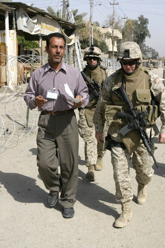FALLUJAH, Iraq - Lt. Col. William M. Jurney, 1st Battalion, 6th Marine Regiment's battalion commander, right, walks with Sgt. Maj. T. F. Hall, 1st Battalion, 6th Marine Regiment sergeant major, middle, and an Iraqi worker through the Jolan Park compound park here.  1st Battalion, 6th Marine Regiment personnel are assisting the Iraqi Interim Force and Public Order Battalion police force to provide security in the distribution of $100 million worth of reparation payments to citizens to rebuild their homes and businesses from damages done during the assault on Fallujah last year.
