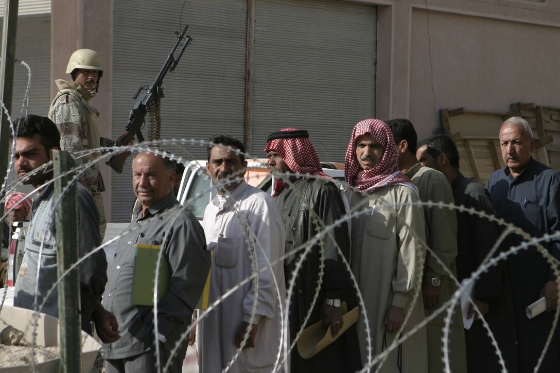 FALLUJAH, Iraq - Bader Khumar, a soldier with the Iraqi Interim Forces' 4th Company, 3rd Battalion, 2nd Brigade, watches over a crowd outside the Jolan Park compound here.  The IIF and Public Order Battalion police force are working beside Regimental Combat Team-8 personnel to provide security in the distribution of $100 million worth of reparation payments to citizens to rebuild their homes and businesses from damages done during the assault on Fallujah last year.