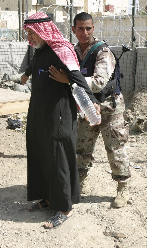 FALLUJAH, Iraq - An Iraqi policeman with the Public Order Battalion searches a resident here before he enters the Jolan Park compound here.  Interim Iraqi Forces are working alongside Regimental Combat Team-8 personnel to provide security in the distribution of $100 million worth of reparation payments to citizens to rebuild their homes and businesses from damages done during the assault on Fallujah last year.