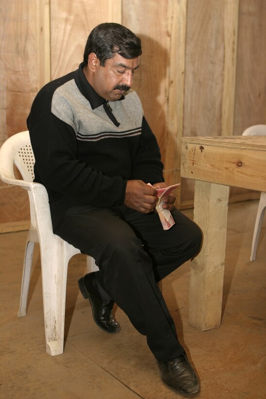 FALLUJAH, Iraq - An Iraqi man counts money he received at the Jolan Park compound here.  Iraqi personnel are giving many of Fallujah's residents reparation money to pay for damages done during the assault on Fallujah last year.