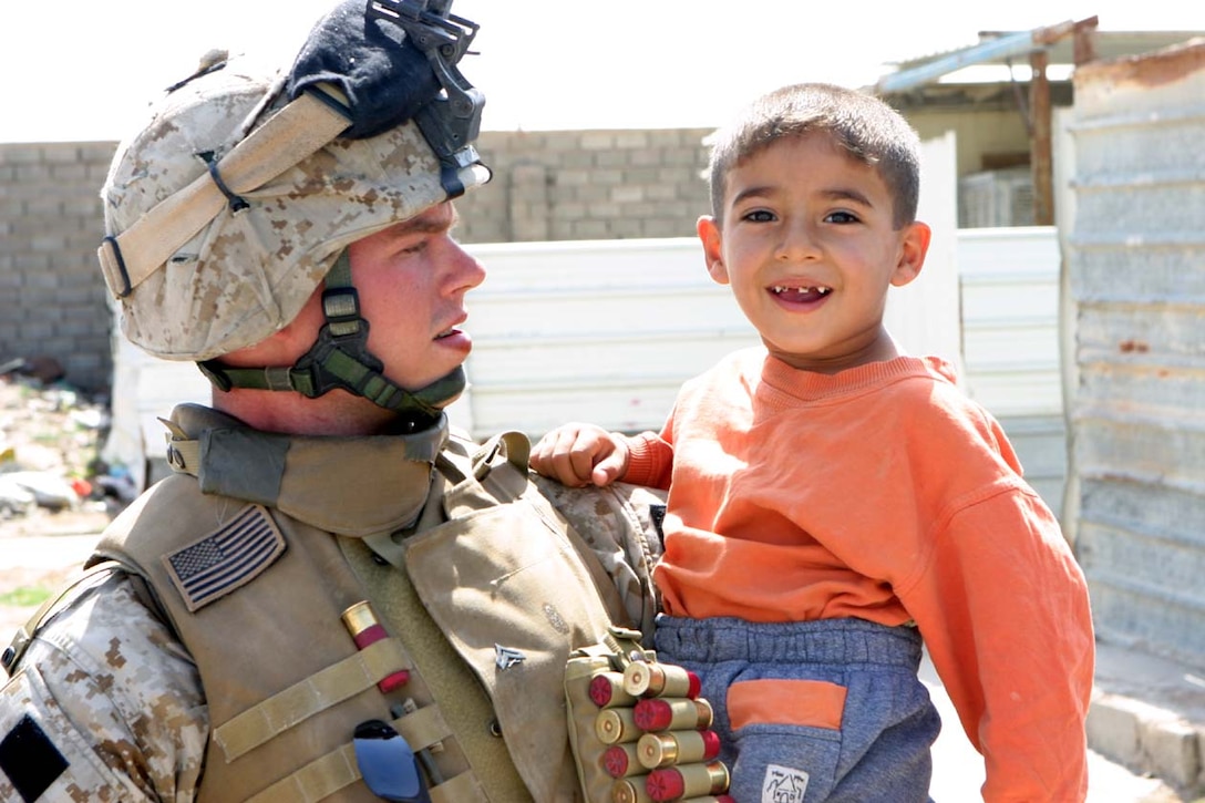 CAMP FALLUJAH, IRAQ -- A Marine with  2nd Platoon, Company I, picked up a local Iraqi boy who had been waving and smiling at the Marines as they searched around his families home.  The child wanted his picture taken with him, so he took a moment to take a photo with the child.  Official U.S. Marine Corps photo by Lance Cpl. Athanasios L. Genos