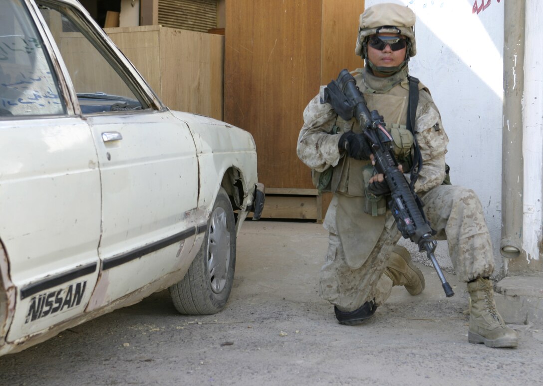 FALLUJAH, Iraq - A Marine with 2nd Squad, 3rd Platoon, Company C, 1st Battalion, 6th Marine Regiment kneels down as he provides security for his patrol passing through the streets here May 28.  The unit is currently conducting security and stability operations alongside Iraqi Security Forces here.