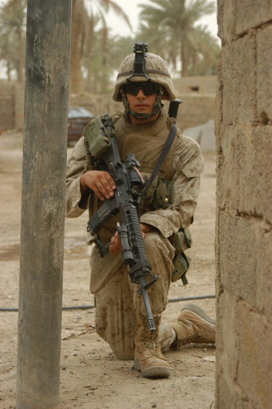 AR RAMADI Iraq (June 29, 2005) - Private First Class Alan J. Maria, a rifleman with 3rd Squad, 4th Platoon, Company B, 1st Battalion, 5th Marine Regiment, takes a knee and provides security around a street corner during a mission in the city here June 28. The 19-year-old from McAllen, Texas and his fellow Marines conducted a patrol through a portion of their company's area of operations to locate enemy sniper positions. Company B's observation post has been taking sporadic sniper fire from the area around it. Photo by: Cpl. Tom Sloan
