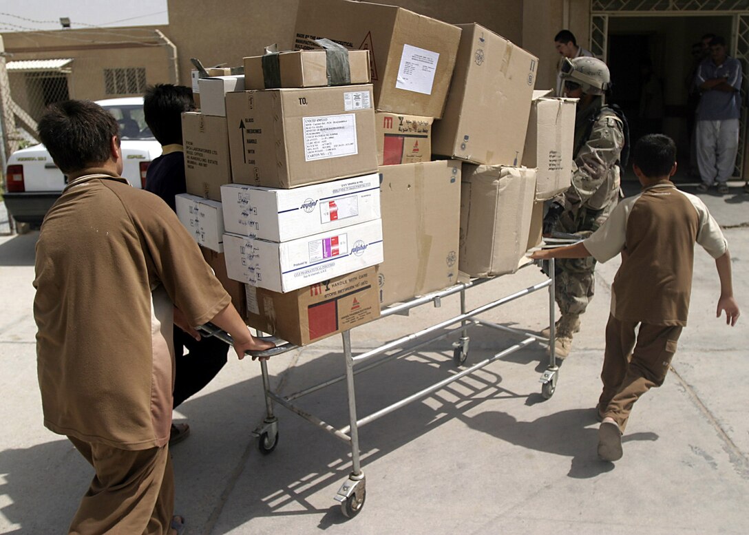 Hit, Al Anbar, Iraq-Local children help ISF soldiers move medical supplies into the local hospital during a visit to distribute surplus medical supplies. (Official USMC Photo by Corporal Ken Melton)