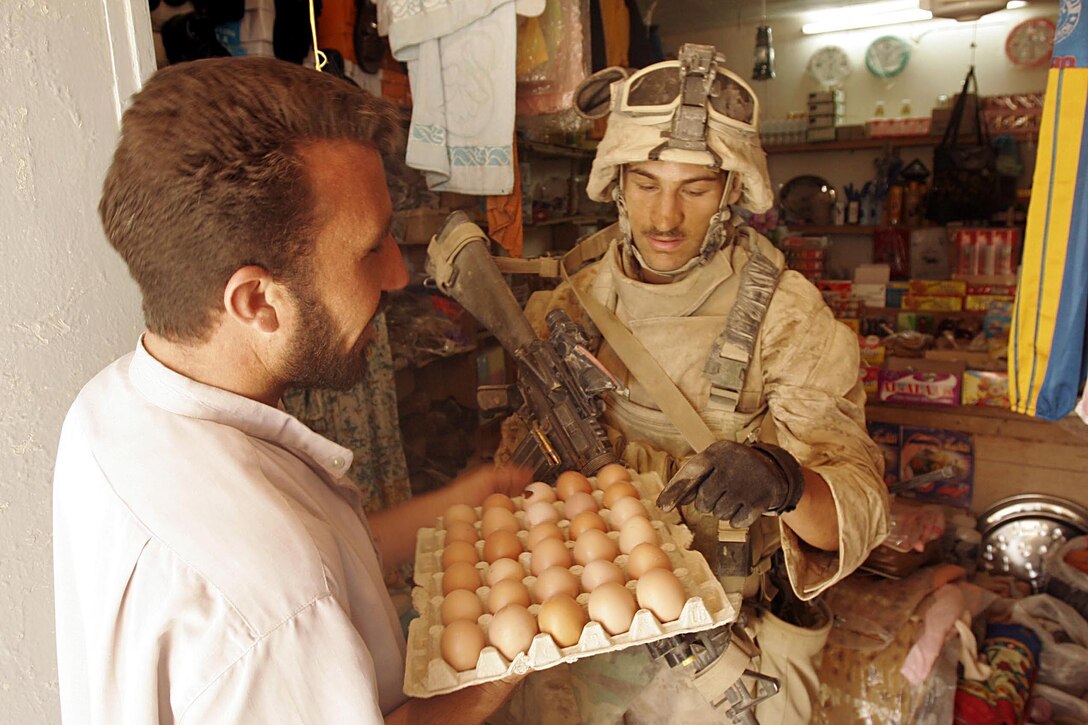 BARWANA, Iraq (October 14, 2005)- Kuwaiti born Cpl. Yousef A. Badou, a 22-year-old scout for 1st Light Armored Reconnaissance Battalion Jump Team uses his Arabic speaking skill to buy from a vendor during  Operation River Gate. Operation River Gate is the effort  to conduct counter-insurgency operations with Iraqi Security Forces to isolate and neutralize anti-Iraqi forces, to support the continued development of Iraqi Security Forces, and to support Iraqi reconstruction and democratic elections in order to create a secure environment that enables Iraqi self-reliance and self-governance. (Official USMC photo by Cpl. Ken Melton)