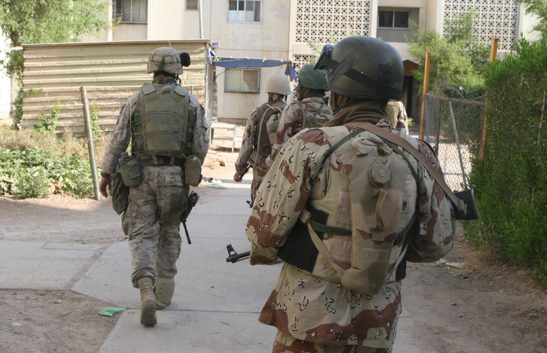 A Marine and Iraqi soldiers of Iraqi Army Platoon, Echo Company, 3rd Reconnaissance Battalion, 2nd Marine Division, walk down a path in between apartment buildings in Ferris Town during Operation Southern Fire in late August. The main objective for the platoon was setting up voting polls for Iraq?s referendum vote held October 15.