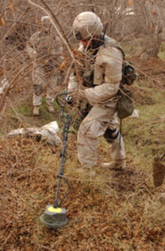 A U.S. Army soldier uses a metal detector to search for weapons during an early morning raid in the small village of Zora, Iraq, on Jan. 9, 2005. Soldiers of Bravo Company, Task Force 82nd Engineers, and Iraqi National Guardsmen uncovered several insurgents and a cache of weapons to include mortars and rocket propelled grenades. 
