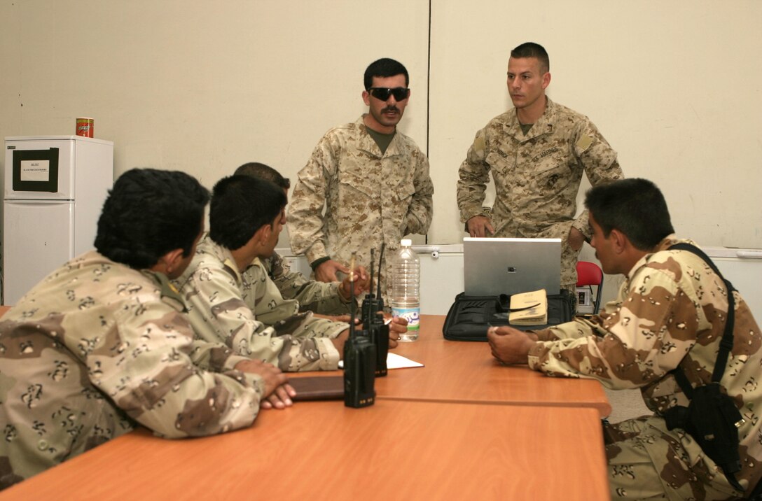 FALLUJAH, Iraq - 2nd Lt. Jason Patrick, 2nd Platoon commander, Company C, 1st Battalion, 6th Marine Regiment, right, stands beside an interpreter as he instructs a class of Iraqi lieutenants here May 29.  The 28-year-old Houston native's unit is currently working alongside these Iraqi soldiers to teach them how to construct terrain models, prepare their troops for combat, and employ several types of weapons against insurgents here.