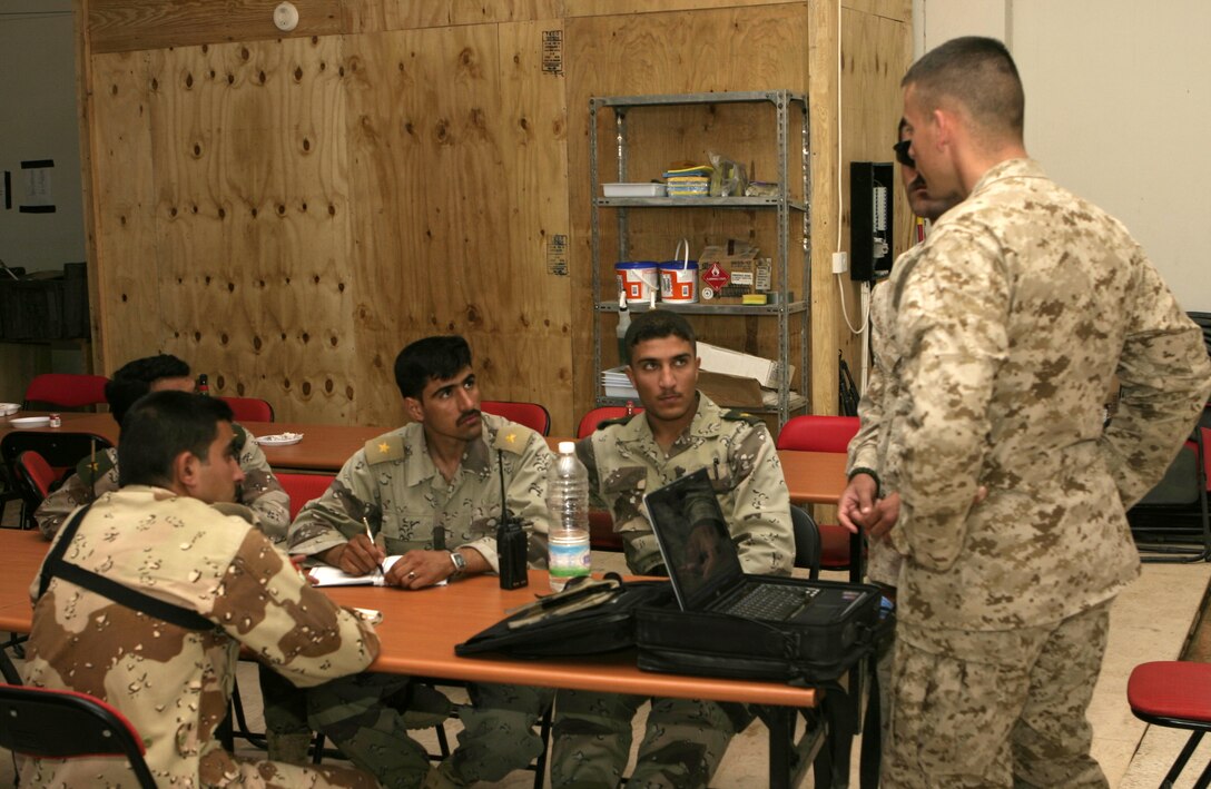 FALLUJAH, Iraq - A group of Iraqi lieutenants listen to a Marine officer as he gives a class aboard an infantry base of operations here May 29.  First Battalion, Sixth Marine Regiment officers are currently working with the Iraqi personnel to teach them how to construct terrain models, prepare their troops for combat, and employ several types of weapons against insurgents here.