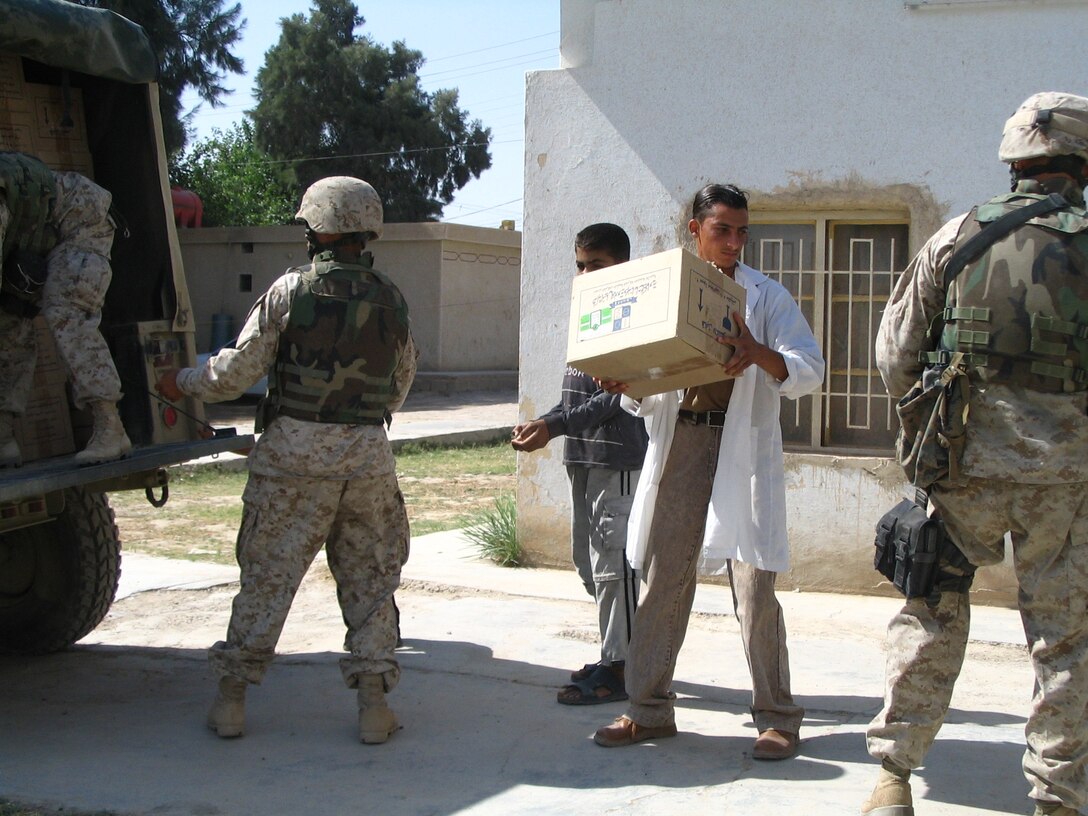 SAQLAWIYAH, Iraq - Dr. Ayad, head of the medical clinic here, helps Marines of the 5th Civil Affairs Group offload supplies from their vehicle May 29.  The civil affairs personnel distributed supplies including 3000 syringes, 36 liters of sanitizer, and 3000 surgical masks.