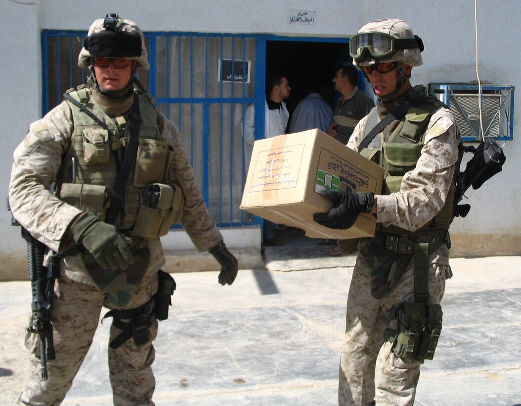 SAQLAWIYAH, Iraq - Sgt. Sean Lawlor, left, and Sgt. Daniel Duff, both Marines with Team 3, Detachment 2, 5th Civil Affairs group, offload boxes of supplies from their vehicle outside the medical clinic here May 29.  The civil affairs personnel distributed supplies including 3000 syringes, 36 liters of sanitizer, and 3000 surgical masks.