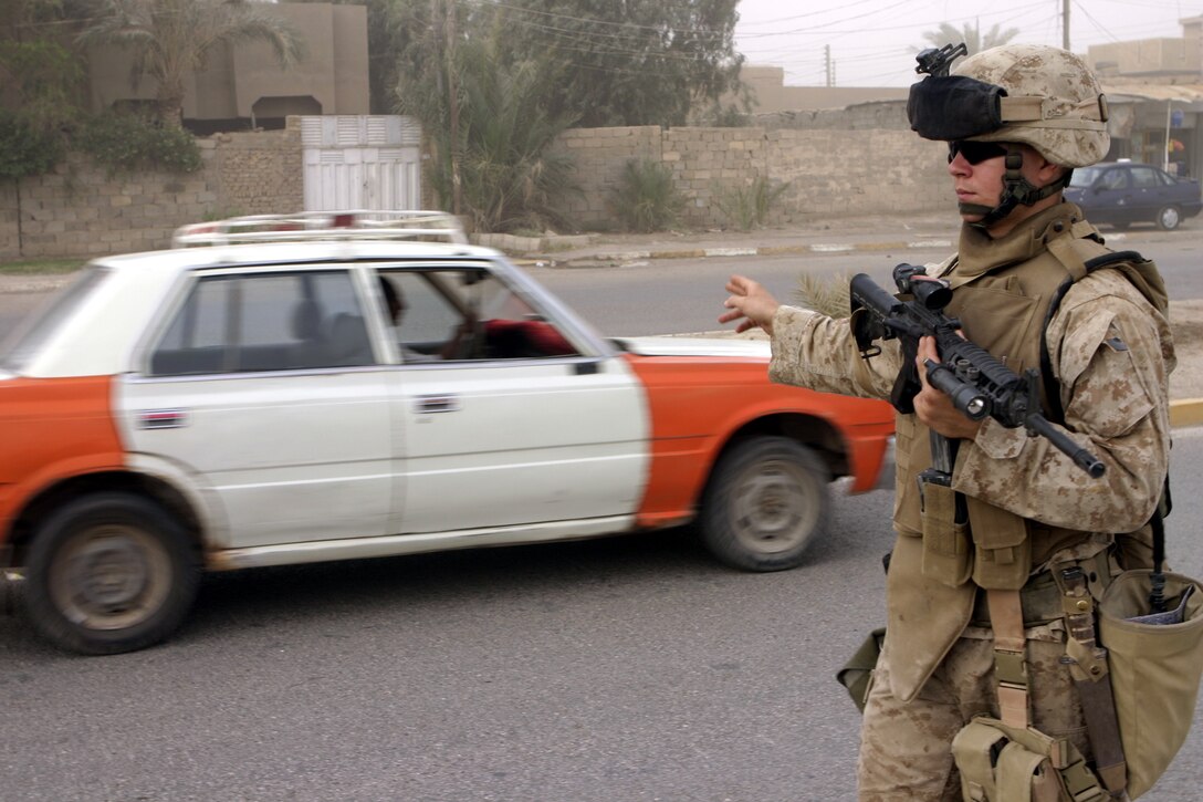 FALLUJAH, Iraq - Lance Cpl. Brad McKee, an infantryman with 2nd Platoon, Company B, 1st Battalion, 6th Marine Regiment, directs traffic while patrolling the city streets June 11.  The 20-year-old Hammond, La. native's unit has been in Iraq approximately 90 days, successfully confiscating numerous weapons and explosives, detaining several known insurgent supporters, and helping Fallujah's residents rebuild their infrastructure.