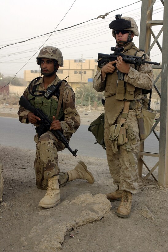 FALLUJAH, Iraq - Lance Cpl. Brad McKee, an infantryman with 2nd Platoon, Company B, 1st Battalion, 6th Marine Regiment, stands beside an Iraqi soldier while providing security for their patrol here June 11.  The 20-year-old Hammond, La. native's unit has been in Iraq approximately 90 days, successfully confiscating numerous weapons and explosives, detaining several known insurgent supporters, and helping Fallujah's residents rebuild their infrastructure.