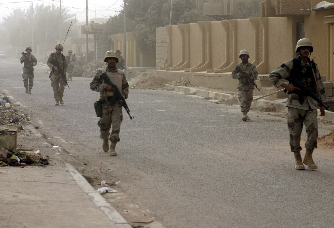FALLUJAH, Iraq - A U.S. Marine patrols through the city streets June 11 amidst several Iraqi soldiers, searching for weapons, explosives and insurgent activity.  The soldiers now conduct many patrols throughout the city with little to no Marine support, and are constantly searching the streets for suspicious activity.