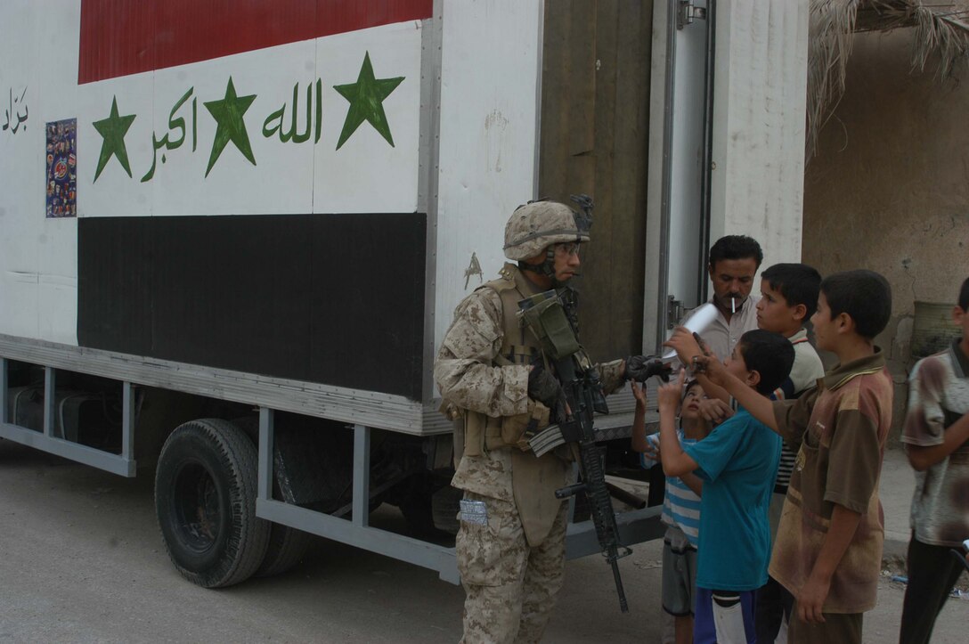 AR RAMADI Iraq (June 29, 2005) -Sergeant Joe A. Salinas, squad leader for 3rd Squad, 4th Platoon, Company B, 1st Battalion, 5th Marine Regiment, stands behind an Iraqi ice cream truck and hands out coalition forces fliers during a mission in the city here June 28. The 35-year-old from San Antonio, Texas and his fellow Marines conducted a patrol through a portion of their company's area of operations to locate enemy sniper positions. Company B's observation post has been taking sporadic sniper fire from the area around it. Photo by: Cpl. Tom Sloan