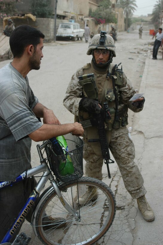 AR RAMADI Iraq (June 29, 2005) -Sergeant Joe A. Salinas, squad leader for 3rd Squad, 4th Platoon, Company B, 1st Battalion, 5th Marine Regiment, checks an Iraqi man's identification card during a mission in the city here June 28. The 35-year-old from San Antonio, Texas and his fellow Marines conducted a patrol through a portion of their company's area of operations to locate enemy sniper positions. Company B's observation post has been taking sporadic sniper fire from the area around it. Photo by: Cpl. Tom Sloan