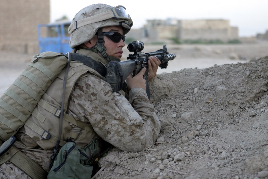 SAQLAWIYAH, Iraq - Lance Cpl. Howard Aycock, a machine gunner with 2nd Platoon, Company A, 1st Battalion, 6th Marine Regiment, provides security while aiming his rifle down a street in a village outside Saqlawiyah codenamed 'Shadyville' June 29.  The 26-year-old Sarasota, Fla. native's unit assisted the Iraqi Security Forces during 'Operation Shadyville,' a mission that netted several suspected insurgent supporters, two improvised explosive devices, and 50 AK-47 assault rifles.