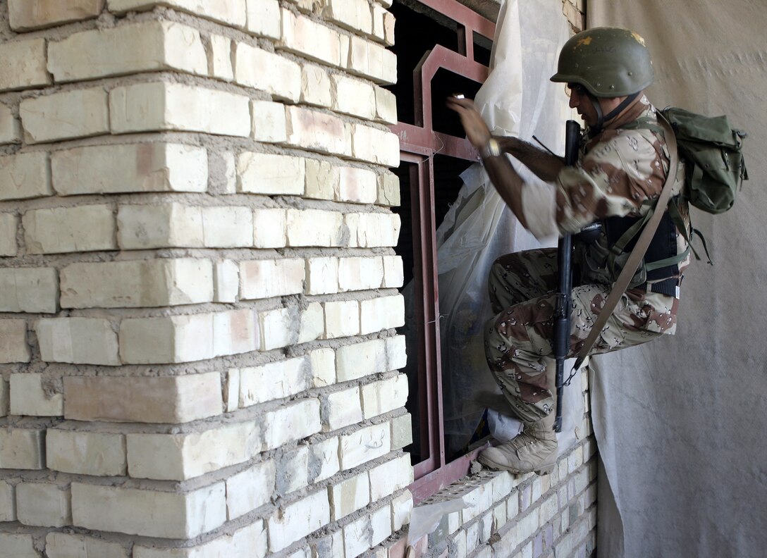 SAQLAWIYAH, Iraq - An Iraqi soldier leaps through an abandoned house's window in a village outside Saqlawiyah codenamed 'Shadyville' June 29.  Iraqi Security Forces assisted Company A, 1st Battalion, 6th Marine Regiment personnel during 'Operation Shadyville,' a mission that netted several suspected insurgent supporters, two improvised explosive devices, and 50 AK-47 assault rifles.