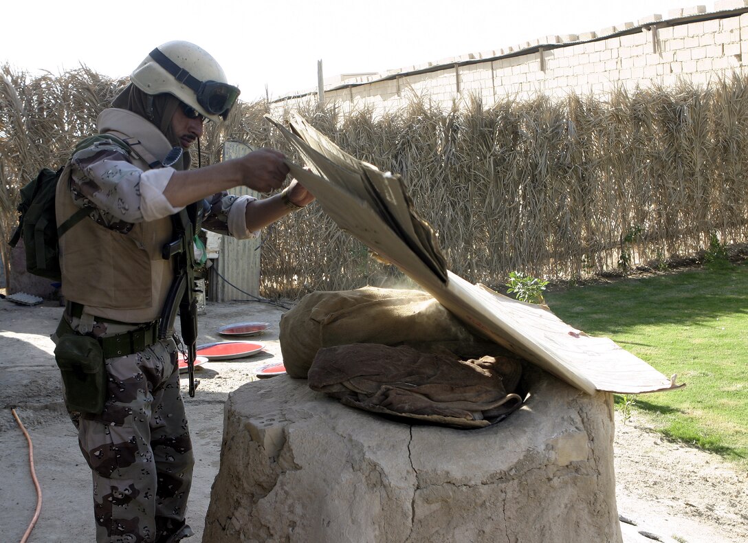 SAQLAWIYAH, Iraq - An Iraqi soldier searches for concealed weapons and explosives near a house in a village outside Saqlawiyah codenamed 'Shadyville' June 29.  Iraqi Security Forces assisted Company A, 1st Battalion, 6th Marine Regiment personnel during 'Operation Shadyville,' a mission that netted several suspected insurgent supporters, two improvised explosive devices, and 50 AK-47 assault rifles.