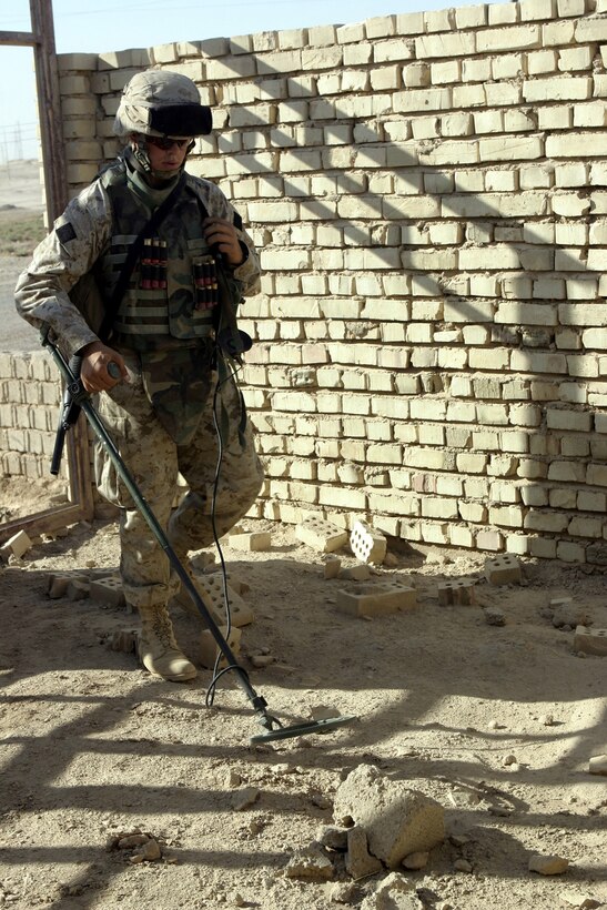 SAQLAWIYAH, Iraq - Pvt. Bryan Smith, a combat engineer with 2nd Platoon, Company A, 2nd Combat Engineer Battalion, uses his AN/PSS-12 metal detector to search for buried weapons and explosive devices in a village outside Saqlawiyah codenamed 'Shadyville' June 29.  Combat engineers assisted Company A, 1st Battalion, 6th Marine Regiment personnel and Iraqi Security Forces during 'Operation Shadyville,' a mission that netted several suspected insurgent supporters, two improvised explosive devices, and 50 AK-47 assault rifles.