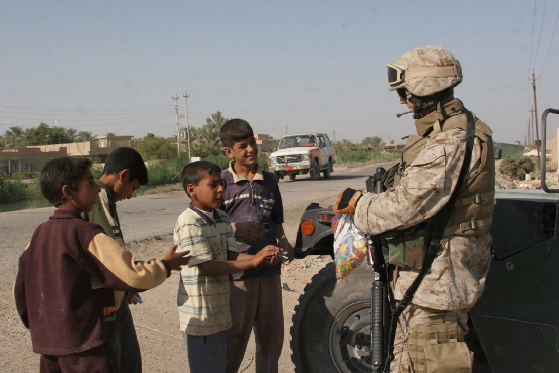 050929-M-2607O-005 AL ANBAR PROVINCE, Iraq -- A Marine from 6th Civil Affairs Group hands out candy to local children during a visit to a project site on Sept. 29.  On almost every trip 6th CAG makes into the Area of Operation they give away school, sporting and hygiene supplies to the local population.
