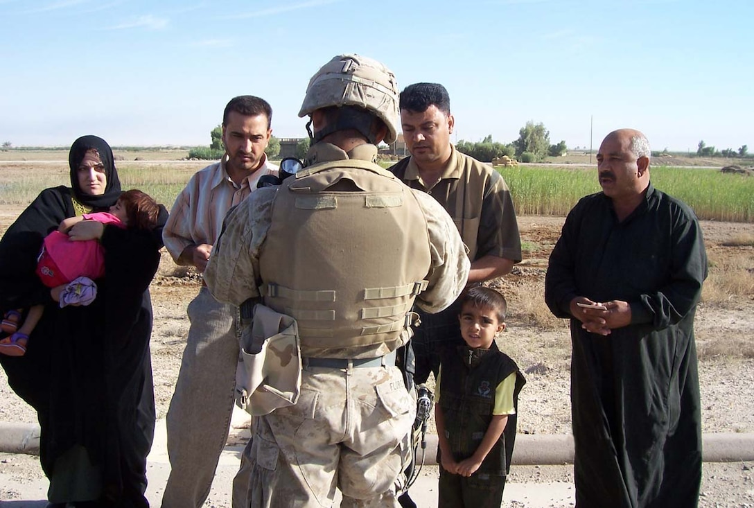 CAMP FALLUJAH, Iraq -- Lance Cpl. Juan M. Flores, a mortarman with Weapons Company, 3rd Battalion, 8th Marine Regiment stops to speak with locals using his language skills learned in the Survival Language Arabic Course he took while preparing for deployment to Operation Iraqi Freedom.  Photo Courtesy of Lance Cpl. Juan M. Flores.