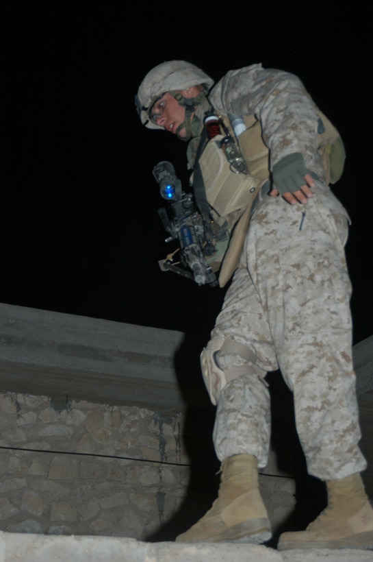 AR RAMADI, Iraq (March 29, 2005) -Keeping his balance, 20-year-old Lance Cpl. Bradford L. Dunn, squad automatic gunner, 3rd Squad, 2nd Platoon, Company C, 1st Battalion, 5th Marine Regiment, from Covington, Ky., walks a narrow, three-inch-wide wall outside an abandoned building his Marines are using as an over watch. Marines with 2nd Platoon, Company C, 1st Battalion, 5th Marines, conducted a late-night combat patrol in a portion of the city here where groups of Iraqis, possibly insurgents, have been seen gathering after curfew hours, which are from 10 p.m. and 6 a.m. The Marines discovered a group of Iraqi teens playing soccer beneath a streetlight and several adults gathered in the street in front of their residences. The Marines finished the patrol without incident and returned to their base camp at Snake Pit. Photo by Cpl. Tom Sloan