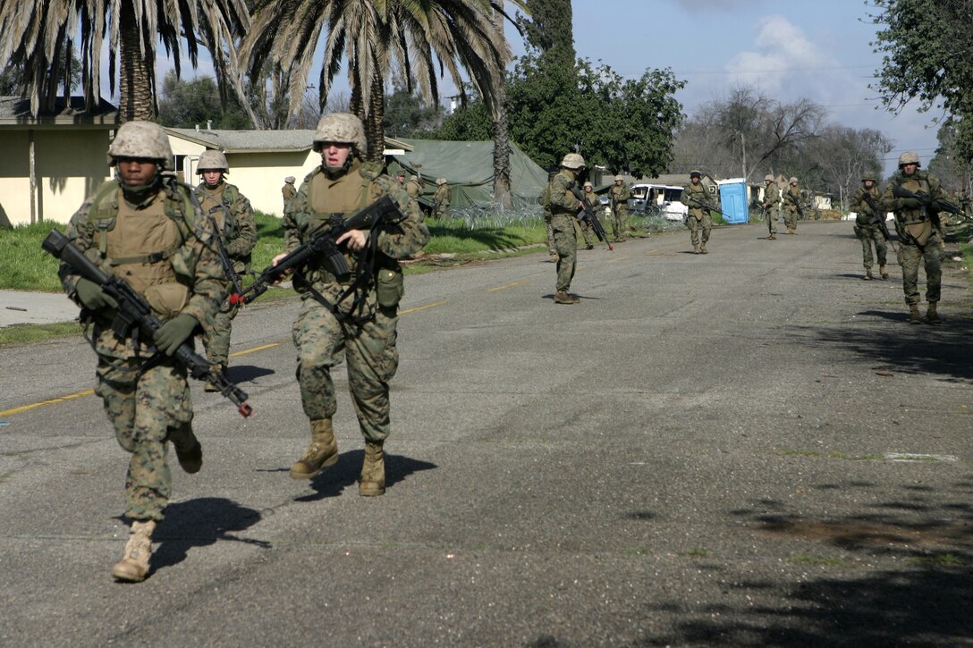 MARCH AIR RESERVE BASE, Calif. - Two Marines with Headquarters and Service Company, 1st Battalion, 6th Marine Regiment, run down a street during a patrol the unit conducted aboard Matilda Village here.  The battalion conducted a Security and Stabilization Operations exercise to prepare for a deployment to Iraq in March.