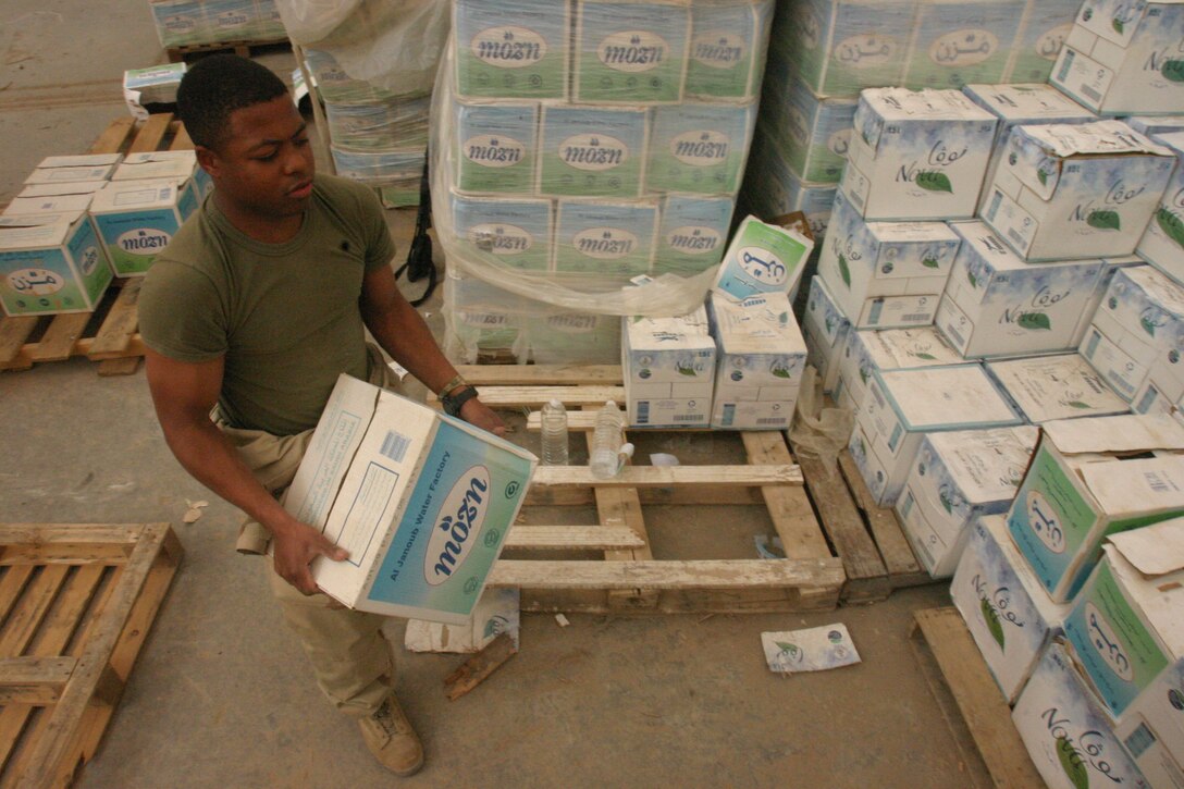 CAMP AL QA'IM, Iraq (April 14, 2005)- Lance Cpl. Robert E. James, III, a warehouse clerk with 3rd Battalion, 2nd Marine Regiment, Regimental Combat Team-2 stacks the battalion's water supply here.  James, a Roanoke, Va., native joined the Marines after his father presented the option to him. The 2003 William Fleming High School gradute describes his high school years as his troubled times and thanks the Corps for his turn around. Official U.S. Marine Corps photo by Lance Cpl. Lucian Friel (RELEASED)