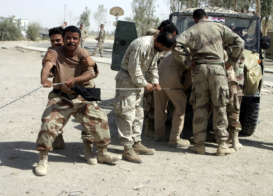 CAMP BAHARIA, Iraq - Iraqi soldiers attempt to help a tow winch pull a vehicle back during a vehicular preventive maintenance class U.S. Marines administered here June 30.  1st Battalion, 6th Marine Regiment motor transport personnel instructed these soldiers on topics such as how to organize a logistics convoy and perform basic preventive maintenance on their vehicles, as part of the battalion's ongoing effort to train the Iraqi Security Forces.