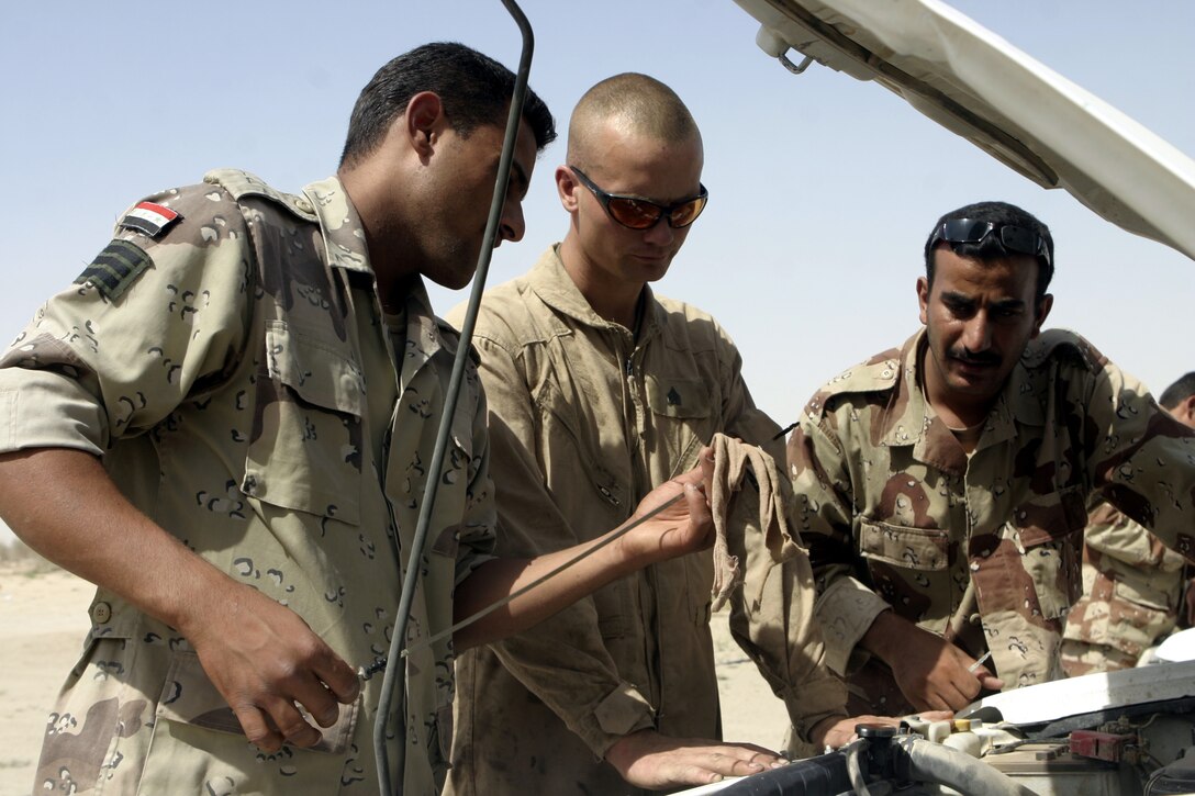 CAMP BAHARIA, Iraq - Sgt. Bob Stoddard, 1st Battalion, 6th Marine Regiment's motor transport maintenance shop chief, observes as Iraqi soldiers check their vehicle's fluids during a preventive maintenance class here June 30.  1st Battalion, 6th Marine Regiment motor transport personnel instructed these soldiers on topics such as how to organize a logistics convoy and perform basic preventive maintenance on their vehicles, as part of the battalion's ongoing effort to train the Iraqi Security Forces.