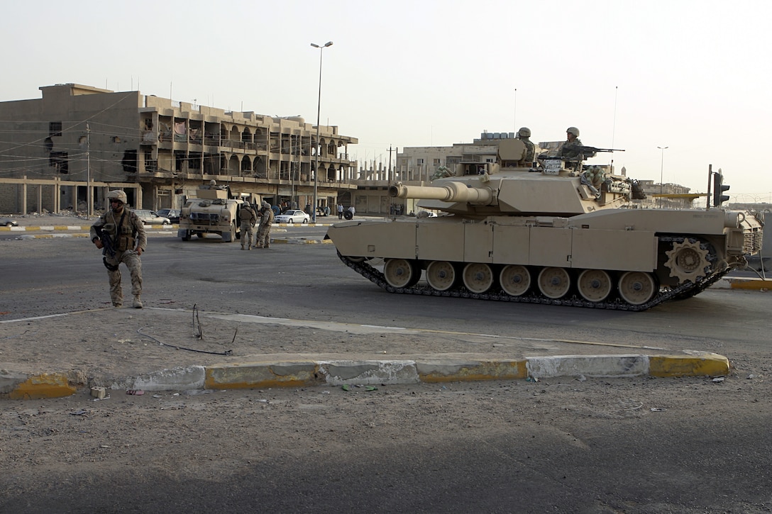 FALLUJAH, Iraq - An M1A1 Abrams tank provides area security alongside a street intersection here beside Marines from Weapons Company, 1st Battalion, 6th Marine Regiment during a recent operation.  M1A1 Abrams tank crewmen from 2nd Tank Battalion, 2nd Marine Division assist ground infantry units provide security and stability throughout western Iraq's Al Anbar province.