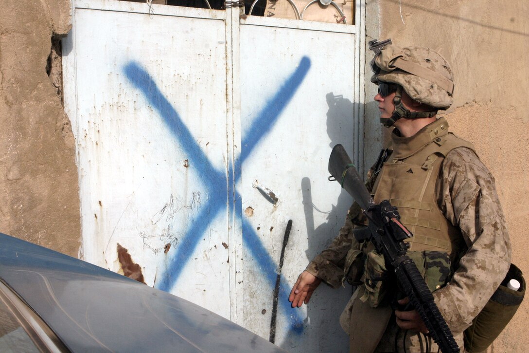 FALLUJAH, Iraq - Lance Cpl. Keith Riley, an infantryman with 1st Platoon, Company C, 1st Battalion, 6th Marine Regiment, prepares to enter and search a home here for weapons and insurgent activity while patrolling the streets July 24.  Company C is currently working alongside Iraqi Security Forces to conduct security and stability operations throughout Fallujah.