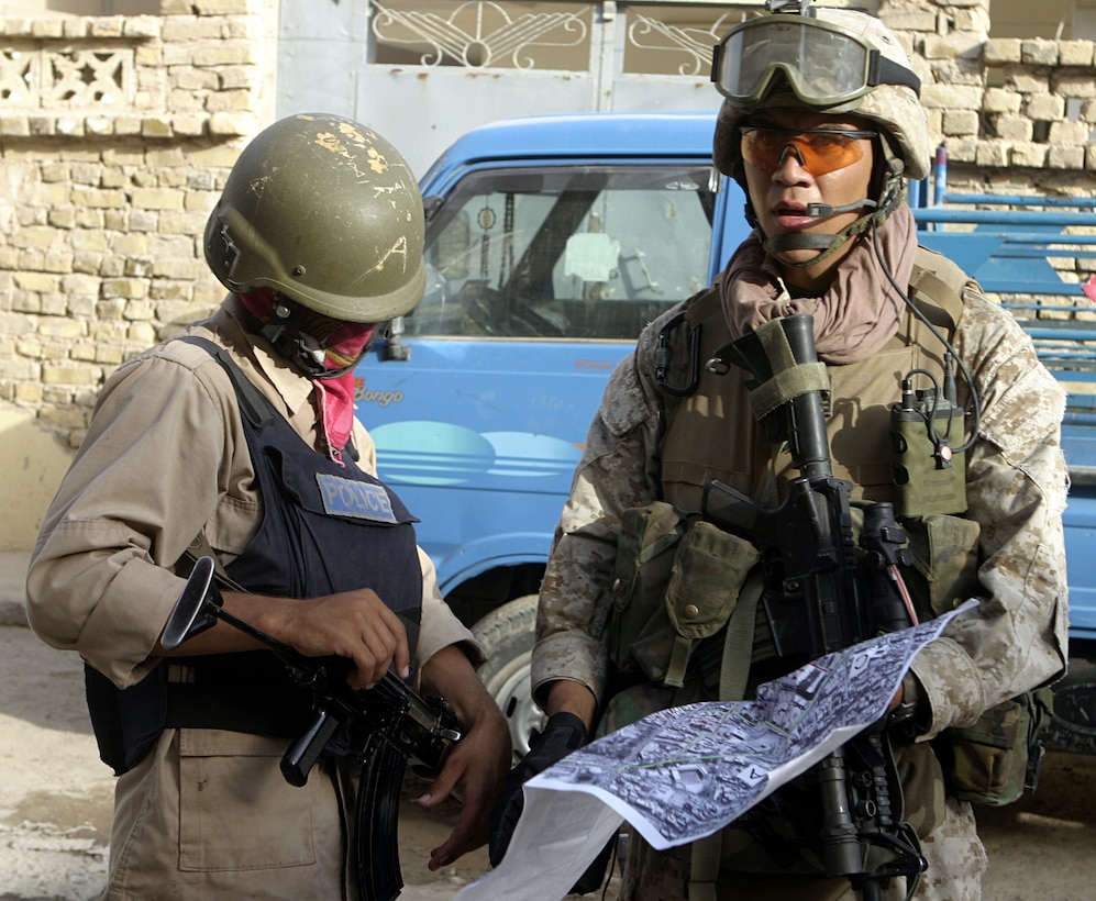 FALLUJAH, Iraq - Cpl. Alex Rangel, 3rd squad leader, 1st Platoon, Company C, 1st Battalion, 6th Marine Regiment, examines a route on a map alongside an Iraqi policeman while patrolling the city streets July 24.  The 22-year-old Middleton, Id. native has been deployed to Iraq's Al Anbar province for several months, where he and fellow Marines assist the Iraqi Security Forces provide security and stability to the country's people.