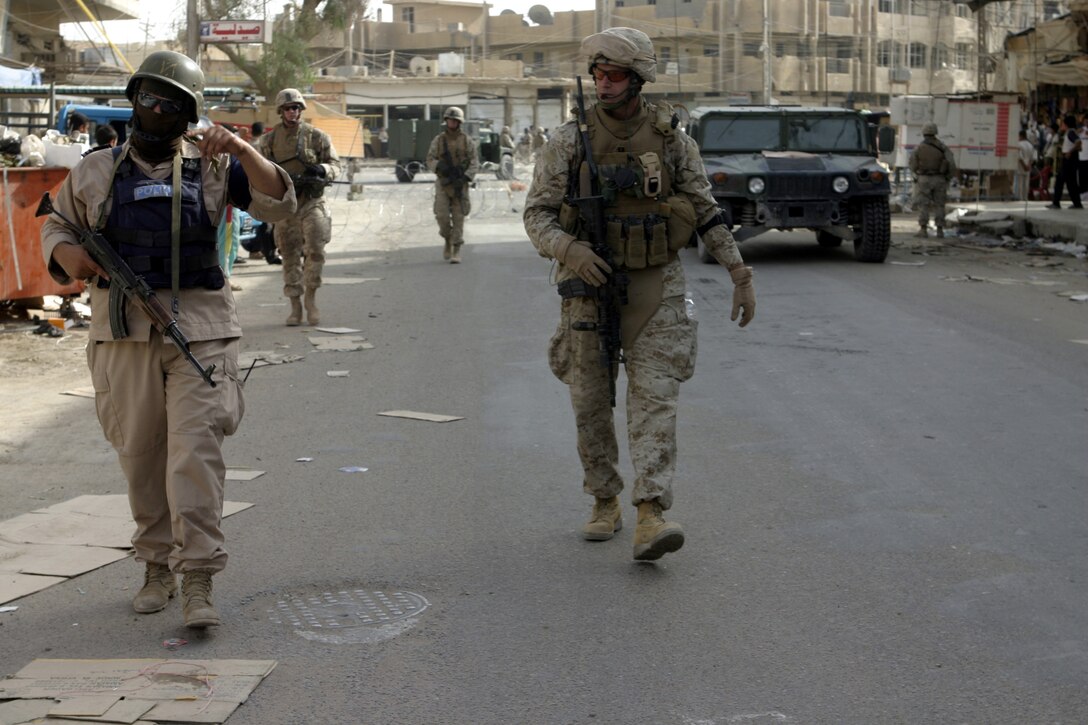 FALLUJAH, Iraq - Capt. Nicholas Neimer, 1st Battalion, 6th Marine Regiment air officer, center; and an Iraqi policeman, left; patrol the city streets alongside Company C, 1st Battalion, 6th Marine Regiment personnel July 24.  Company C is currently working alongside Iraqi Security Forces to conduct security and stability operations throughout Fallujah.
