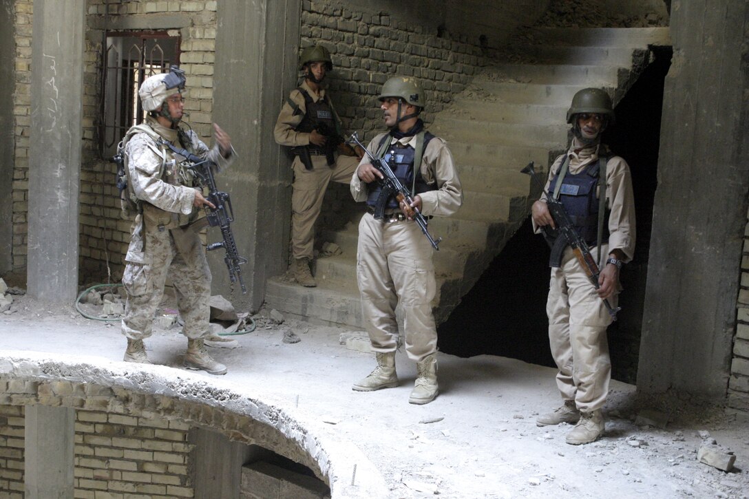 FALLUJAH, Iraq - Cpl. Julian Arechaga, a squad leader with 1st Platoon, Company C, 1st Battalion, 6th Marine Regiment, provides security alongside Iraqi policemen inside a ruined building here July 24.  Company C is currently working alongside Iraqi Security Forces to conduct security and stability operations throughout Fallujah.