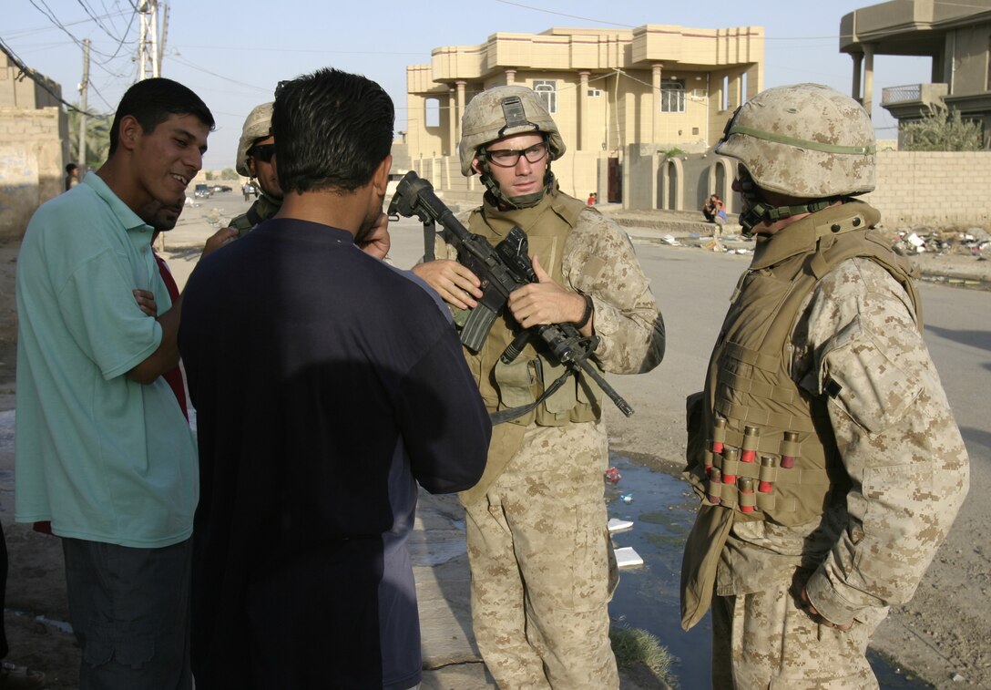 FALLUJAH, Iraq - First Lieutenant Joshua Simpson, 1st Combined Anti-Armor Team's commander, Weapons Company, 1st Battalion, 6th Marine Regiment; center, and other 1st CAAT personnel speak with local residents while patrolling the city streets Aug. 30.  Marines from the battalion's four CAAT platoons routinely patrol the city's streets and alleyways aboard their armored trucks and on foot to search for insurgent activity and improvised explosive devices.