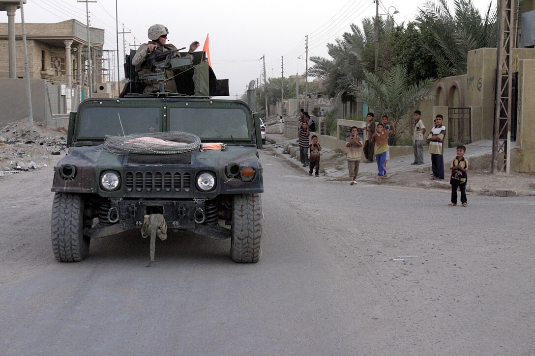 FALLUJAH, Iraq - Iraqi children cheer and wave as 1st Combined Anti-Armor Team, Weapons Company, 1st Battalion, 6th Marine Regiment passes by on patrol here Aug. 30.  Marines from the battalion's four CAAT platoons routinely patrol the city's streets and alleyways aboard their armored trucks and on foot to search for insurgent activity and improvised explosive devices.
