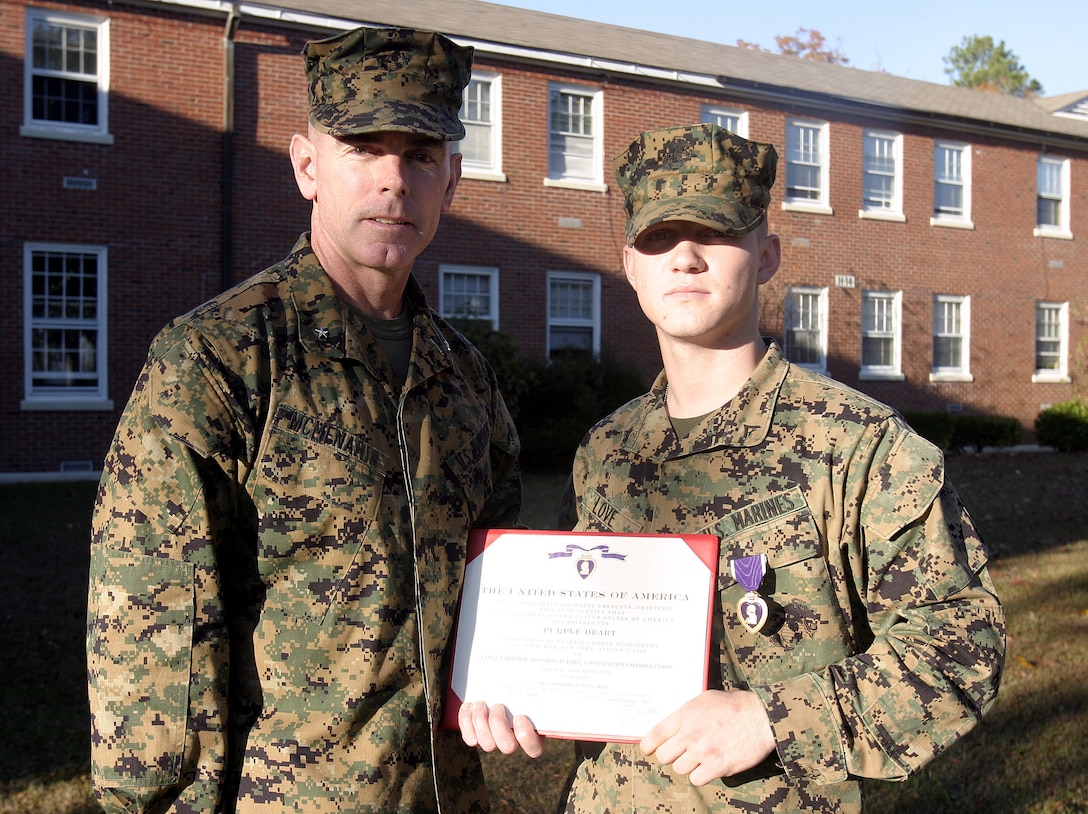 MARINE CORPS BASE CAMP LEJEUNE, N.C. - Lance Cpl. Brandon Love, an infantryman with 2nd Battalion, 2nd Marine Regiment, right, poses for a photo with Brig. Gen. Joseph Mcmenamin, 2nd Marine Division (Rear) commander, shortly after receiving his Purple Heart Medal here Nov. 30.  Love, a 19-year-old Charlottesville, Va. native, suffered shrapnel wounds and busted eardrums when an improvised explosive device detonated near his convoy while he and his unit had been conduction combat operations in Iraq's Al Anbar province in September.
