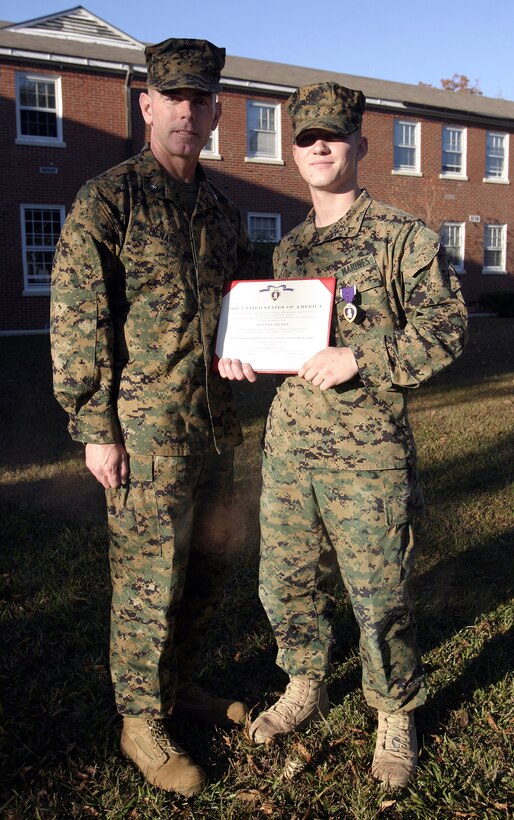 MARINE CORPS BASE CAMP LEJEUNE, N.C. - Lance Cpl. Brandon Love, an infantryman with 2nd Battalion, 2nd Marine Regiment, right, poses for a photo with Brig. Gen. Joseph Mcmenamin, 2nd Marine Division (Rear) commander, shortly after receiving his Purple Heart Medal here Nov. 30.  Love, a 19-year-old Charlottesville, Va. native, suffered shrapnel wounds and busted eardrums when an improvised explosive device detonated near his convoy while he and his unit had been conduction combat operations in Iraq's Al Anbar province in September.