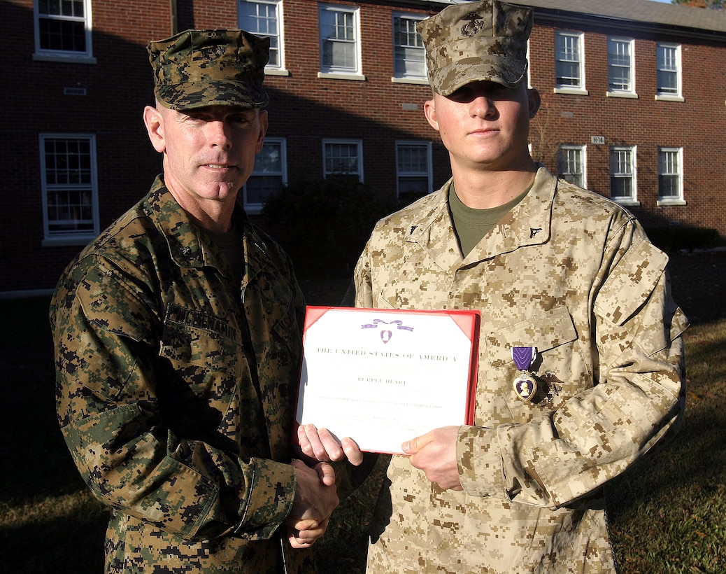 MARINE CORPS BASE CAMP LEJEUNE, N.C. - Lance Cpl. Ryan Cahill, an infantryman with 2nd Battalion, 2nd Marine Regiment, right, poses for a photo with Brig. Gen. Joseph Mcmenamin, 2nd Marine Division (Rear) commander, shortly after receiving his Purple Heart Medal here Nov. 30.  Cahill, a 19-year-old Baton Rouge, La. native, suffered shrapnel and other wounds in September after an improvised explosive device detonated near the vehicle he had been driving, causing it to tumble into a nearby canal.  Cahill and his teammates had been conducting an IED sweep in Karmah, a city outside Fallujah.
